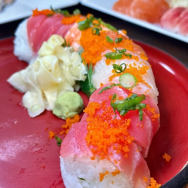 Colorful sushi roll with tuna, shrimp, roe, and scallions, served with ginger and wasabi.